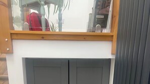 Ein grauer Kleiderschrank mit zwei Türen und einem Holzregal darüber.
