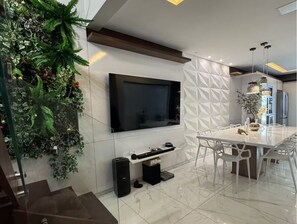 A modern kitchen with a flat-screen TV, a dining table, and a built-in plant wall. - Entire house with air conditioning and 3 bedrooms. (Ipatinga)