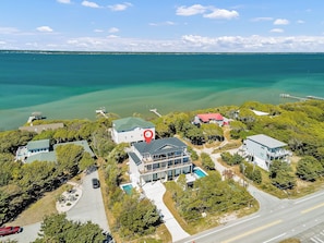 An aerial view of a coastal property with a large house, a swimming pool, and a dock extending into the water. - New 2025 Build | Private Pool, Elevator | Ocean & Sound Views | DOGS OK (Emerald Isle)