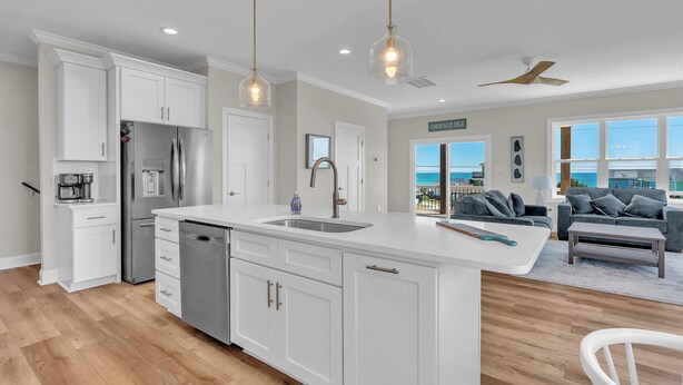Een moderne keuken met een groot eiland, witte kasten en hanglampen.