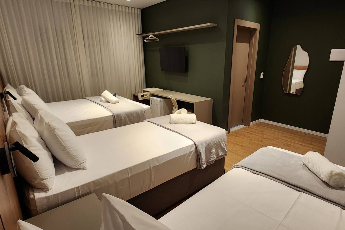 Une chambre d’hôtel avec deux lits, une télévision, un miroir et un plancher en bois.