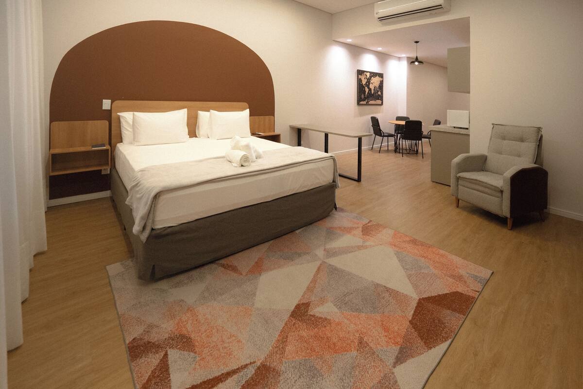 Une chambre d’hôtel moderne équipée d’un grand lit, d’un bureau, d’une chaise et d’un petit coin salon.