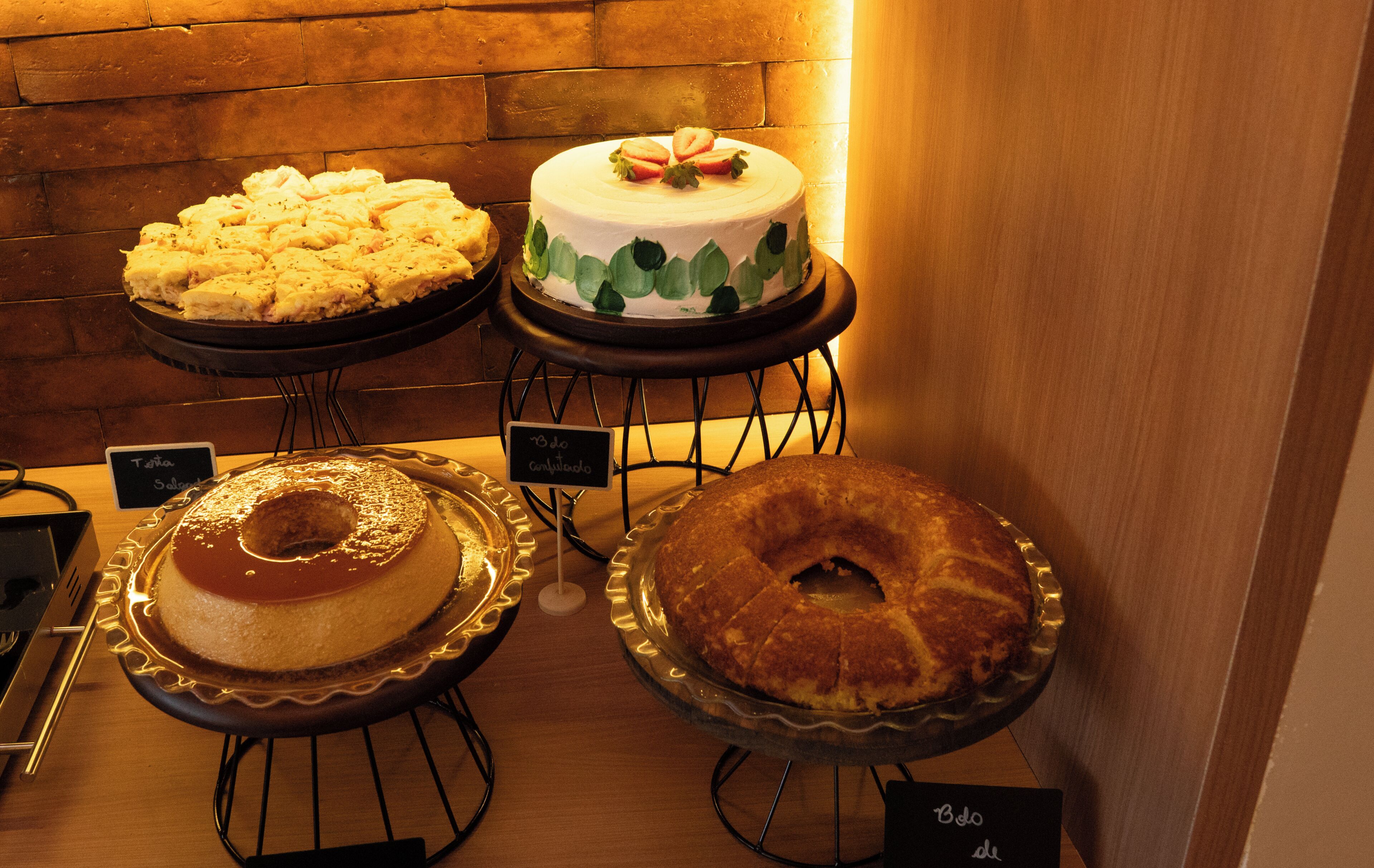 Exhibición de pasteles sobre pedestales con etiquetas.