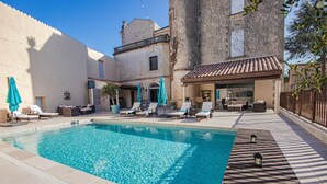 A swimming pool with lounge chairs and umbrellas, a tiled deck, and a building with a tiled roof. - Chateau Antares - Eight Bedroom Castle, Sleeps 16 (Marcorignan)