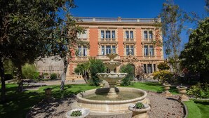 A large, historic building with a symmetrical facade, a central entrance, and a fountain in the foreground. - Chateau Antares - Eight Bedroom Castle, Sleeps 16 (Marcorignan)