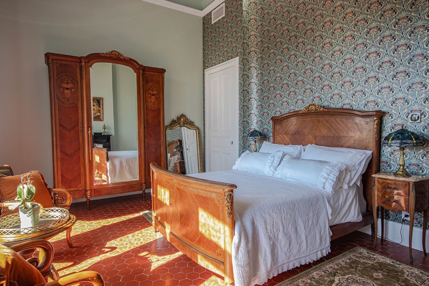 A bedroom with a wooden bed, a wardrobe, a mirror, and a patterned wallpaper.