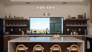 Een moderne keuken met een groot eiland, houten barstoelen en uitzicht op de omgeving.