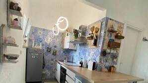 A compact kitchen with a wooden island, white bar stools, a refrigerator, and a patterned backsplash. - Piccolo Resort sul Conero – Relax con Vista Mare tra Natura e Silenzio (Marche)