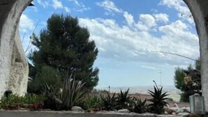 An arched window with a view of a landscape including trees and a distant structure. - Piccolo Resort sul Conero – Relax con Vista Mare tra Natura e Silenzio (Marche)