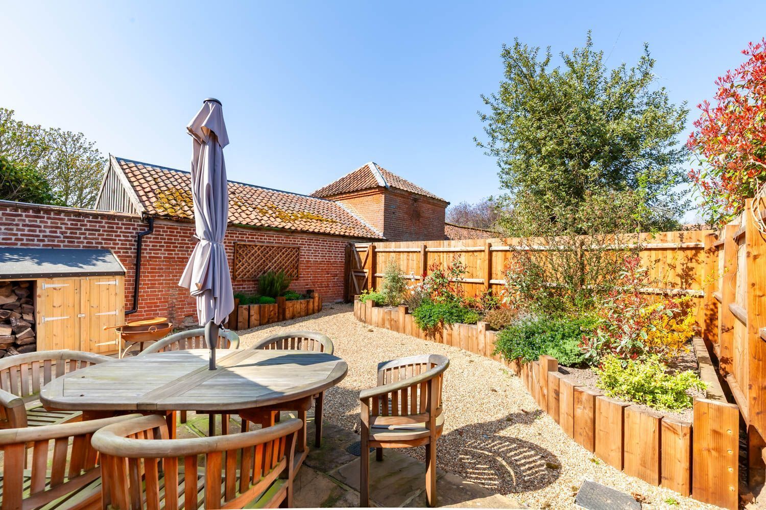 A patio with wooden furniture, a covered table, and a wooden fence.