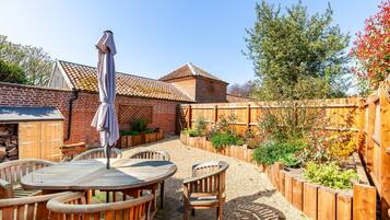 A patio with wooden furniture, a covered table, and a wooden fence.