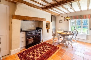 A kitchen with a stove, cabinets, and a dining area with chairs and a table.