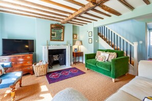 A living room with a fireplace, a green sofa, a television, and a staircase.
