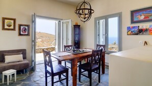 A dining area with a table, chairs, a chandelier, and a view of the sea. - Villa Kea Royale - Two Bedroom Villa, Sleeps 5 (Kastriani)