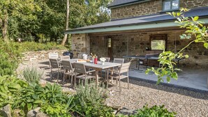 A stone house with a patio area, outdoor seating, and a stone wall. - Welsh Coach House - Five Bedroom Villa, Sleeps 9 (Tan-y-groes)