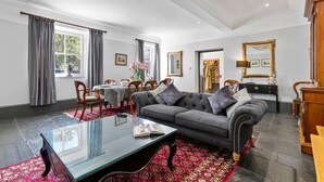 A living room with a sofa, coffee table, and dining area. - Welsh Coach House - Five Bedroom Villa, Sleeps 9 (Tan-y-groes)