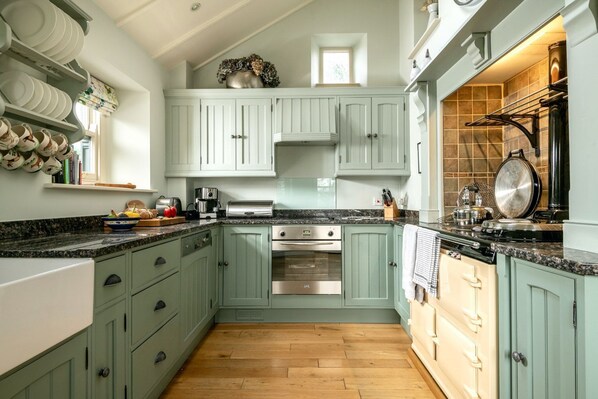 A kitchen with light green cabinets, a stainless steel oven, and a granite countertop.