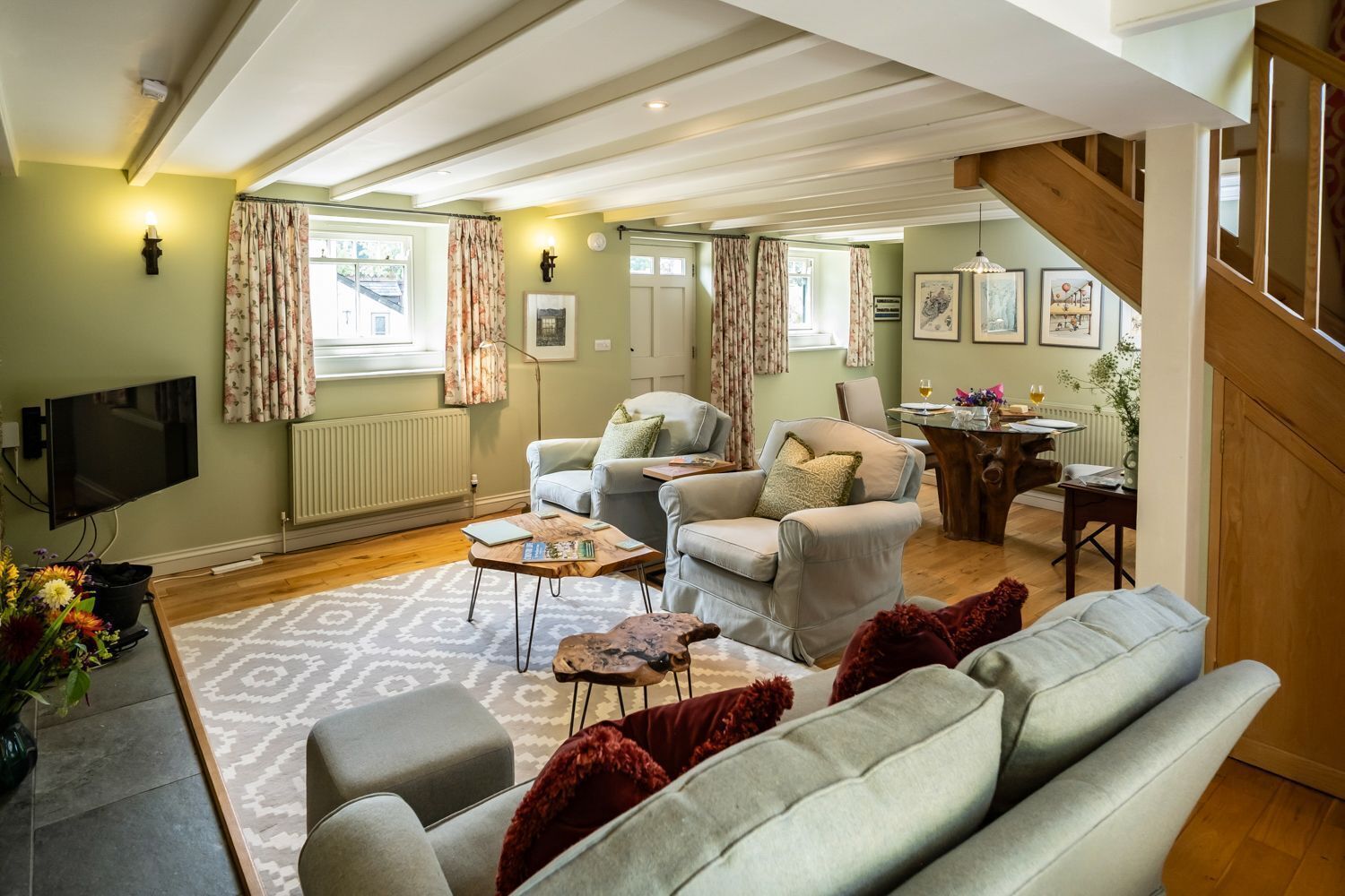 A spacious living room with a sofa, armchairs, a coffee table, and a dining area with a table and chairs.