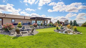 Propiedad residencial con patio, mobiliario exterior, un pequeño estanque y un césped bien cuidado.