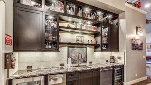 Una cocina con armarios oscuros, encimera de mármol y varios electrodomésticos.