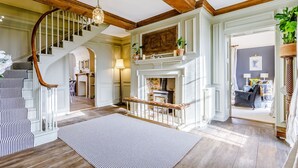A spacious living room with a fireplace, a staircase with striped railings, and a view into another room. - Sandon Manor - Seven Bedroom Villa, Sleeps 16 (Sandon)