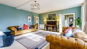 A living room with a sofa, a chair, a piano, and a rug. - Sandon Manor - Seven Bedroom Villa, Sleeps 16 (Sandon)