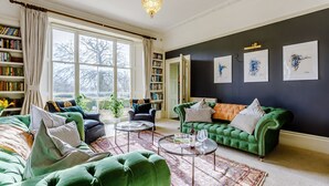 A living room with a green sofa, a coffee table, and a bookshelf. - Sandon Manor - Seven Bedroom Villa, Sleeps 16 (Sandon)