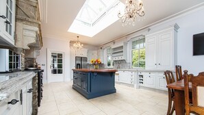 A spacious kitchen with a central island, white cabinetry, and a chandelier. - Pendragon Manor - Nine Bedroom Villa, Sleeps 18 (Cilybebyll Pontardawe)