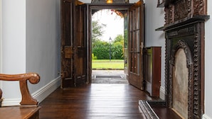 An open doorway leading to a garden, with a wooden bench and a fireplace on the left. - Pendragon Manor - Nine Bedroom Villa, Sleeps 18 (Cilybebyll Pontardawe)