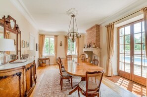 A dining room with a large wooden table, chairs, a chandelier, and a fireplace. - Maison Merisier - Six Bedroom Villa, Sleeps 14 (Montpon-Ménestérol)