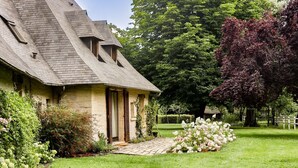 A house with a sloped roof, a stone exterior, and a well-maintained garden with flowers and shrubs. - La Faisane - Five Bedroom Villa, Sleeps 10 (Épaignes)