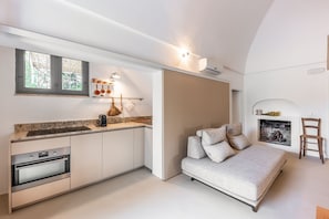Eine kompakte Küche mit Einbauofen, ein Essbereich mit einer Couch und ein Kamin.