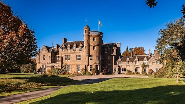 A large, historic castle-like building with multiple towers and a central courtyard.