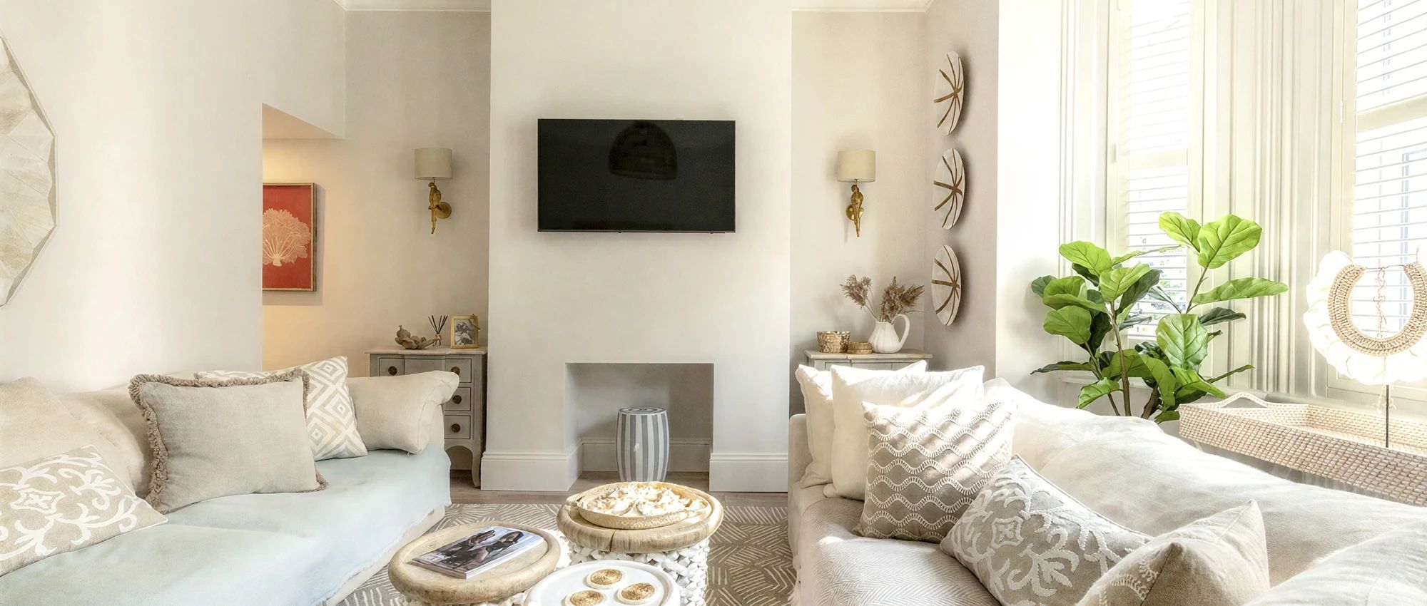 A living room with a sofa, a coffee table, a fireplace, and a television mounted on the wall.