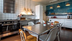 A modern kitchen with a central island, stainless steel appliances, and pendant lighting. - Spinnaker House - Eight Bedroom Villa, Sleeps 16 (Beaumaris)