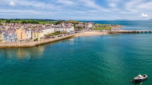 A coastal town with a waterfront promenade, a pier, and a small boat docked near the shore. - Spinnaker House - Eight Bedroom Villa, Sleeps 16 (Beaumaris)