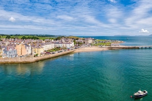 Une ville côtière dotée d’une promenade en bord de mer, d’une jetée et d’un petit bateau amarré près du rivage.