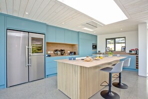 A modern kitchen with a central island, stainless steel appliances, and a view of the outdoors.