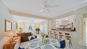 A dining area with a glass table, chairs, and a ceiling fan. - 3BR Townhouse in Holetown w/pool, Steps from Beach! (Holetown)