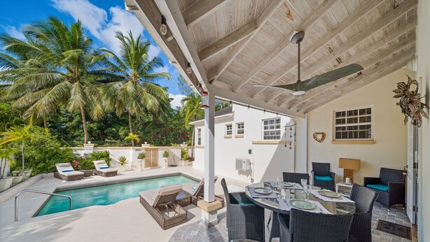 A covered outdoor area with a pool, lounge chairs, and a dining table. - 3BR Townhouse in Holetown w/pool, Steps from Beach! (Holetown)