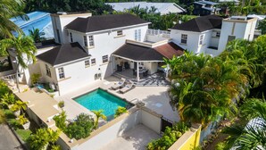 A multi-story residential building with a swimming pool, surrounded by lush greenery and palm trees. - 3BR Townhouse in Holetown w/pool, Steps from Beach! (Holetown)