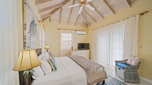 A bedroom with a bed, a television, a ceiling fan, and a window with curtains. - 3BR Townhouse in Holetown w/pool, Steps from Beach! (Holetown)