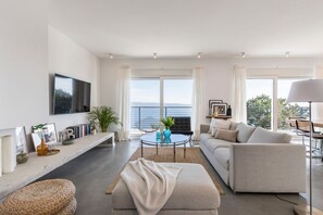 Ein modernes Wohnzimmer mit einer Couch, einem Couchtisch und einem an der Wand montierten Fernseher.
