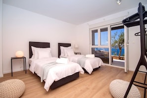 Ein modernes Hotelzimmer mit zwei Betten, einem Balkon und Meerblick.