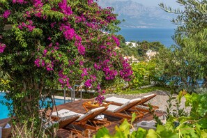 A poolside area with lounge chairs and a view of the sea. - Villa Bufo - Four Bedroom Villa, Sleeps 10 (Mimice)