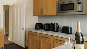 Una cucina moderna con mobili in legno, un forno a microonde in acciaio inossidabile e una bottiglia di vino sul bancone.