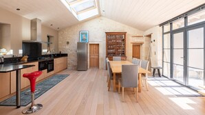 A modern kitchen with a dining area, skylights, and a stone wall.