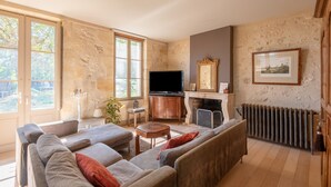 A living room with a sofa, TV, fireplace, and stone walls.