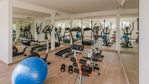Ein Fitnessstudio mit Trainingsgeräten, einem blauen Übungsball und einer Spiegelwand.