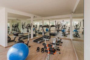 Ein Fitnessstudio mit Trainingsgeräten, einem blauen Übungsball und einer Spiegelwand.